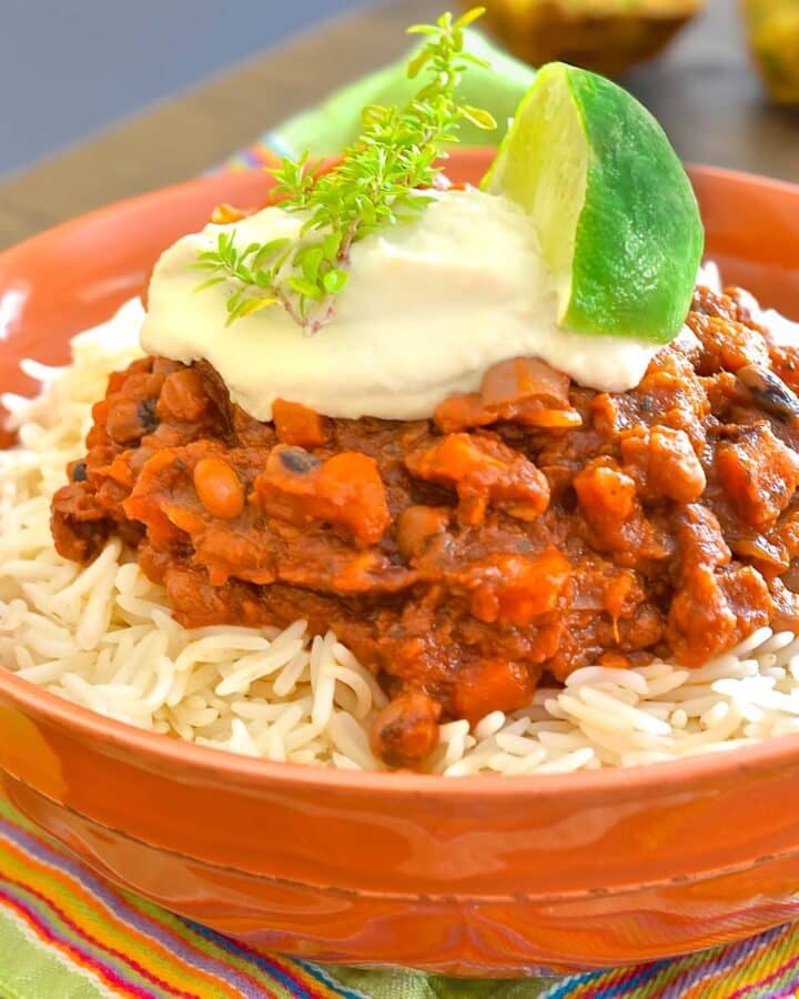 a bowl of chili topped with sour cream and lime