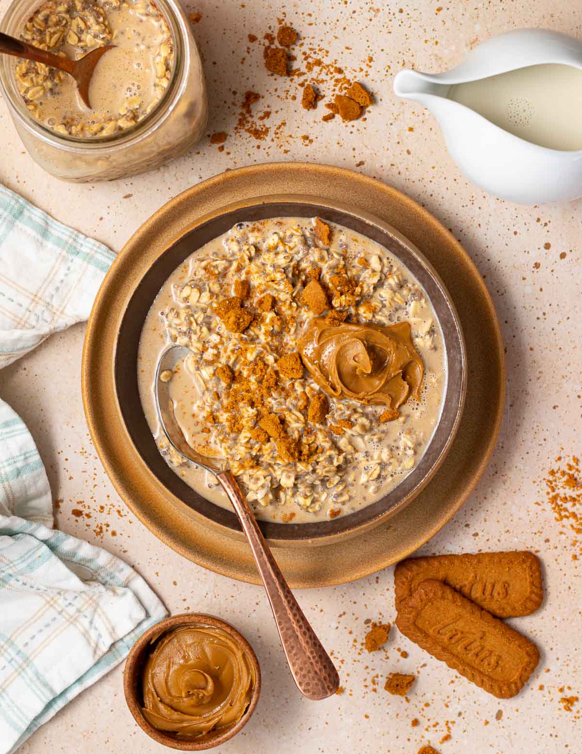 a bowl of Biscoff overnight oats surrounded by cookies, a bowl of cookie butter and a jar of overnight oats