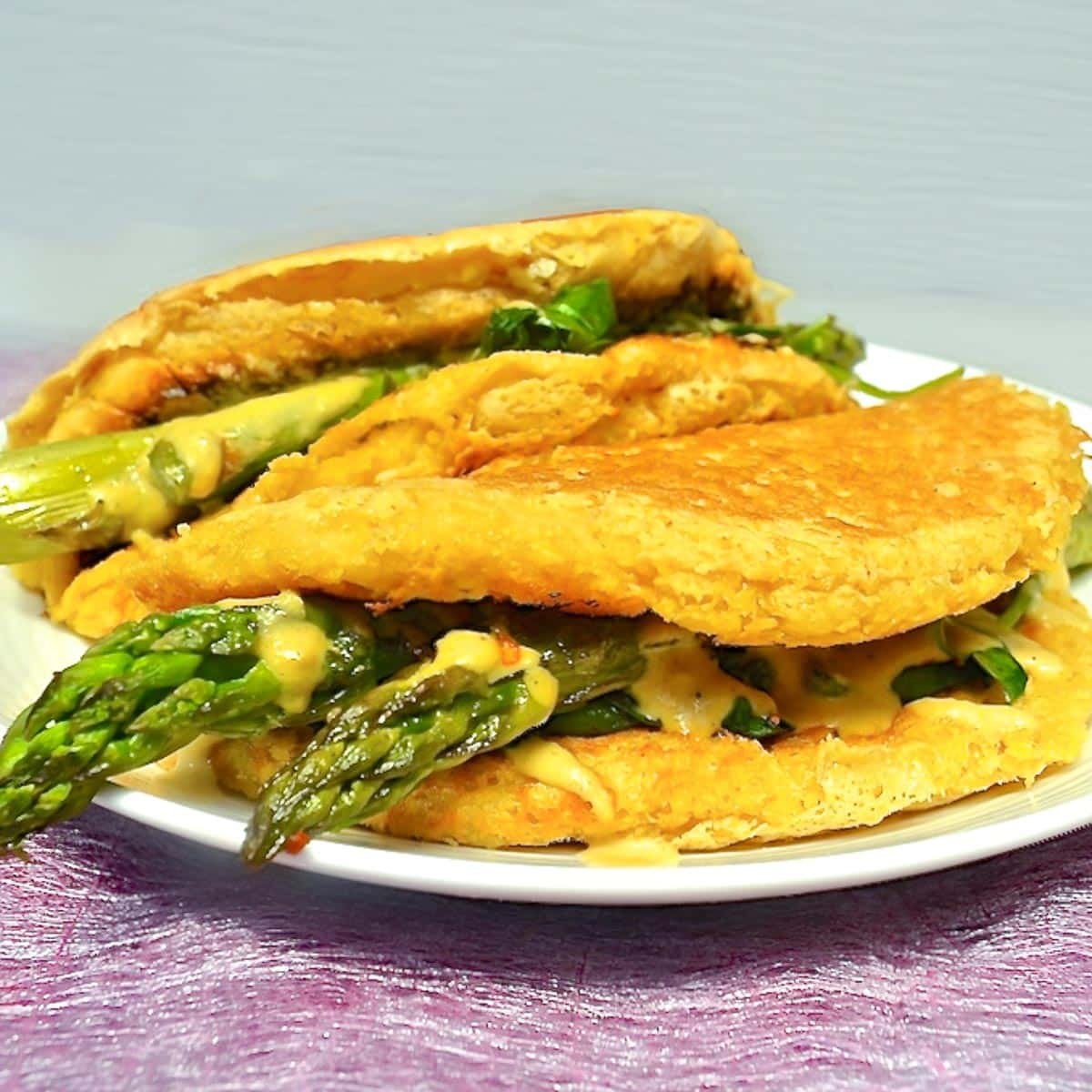 a vegan omelette stuffed with asparagus and dairy-free cheese sauce