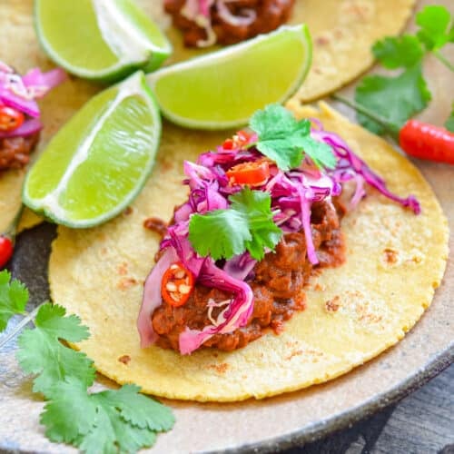 a flat tortilla topped with spicy lentils and red cabbage slaw