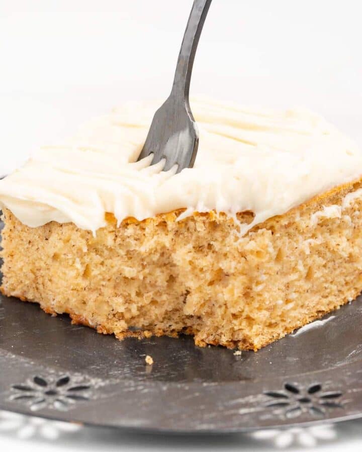 a piece of frosted banana cake with a corner missing