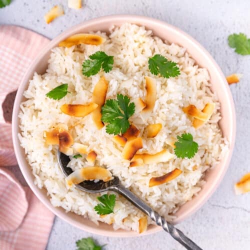 a bowl of coconut basmati rice garnished with toasted coconut and cilantro