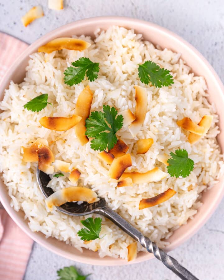 a bowl of coconut basmati rice garnished with toasted coconut and cilantro