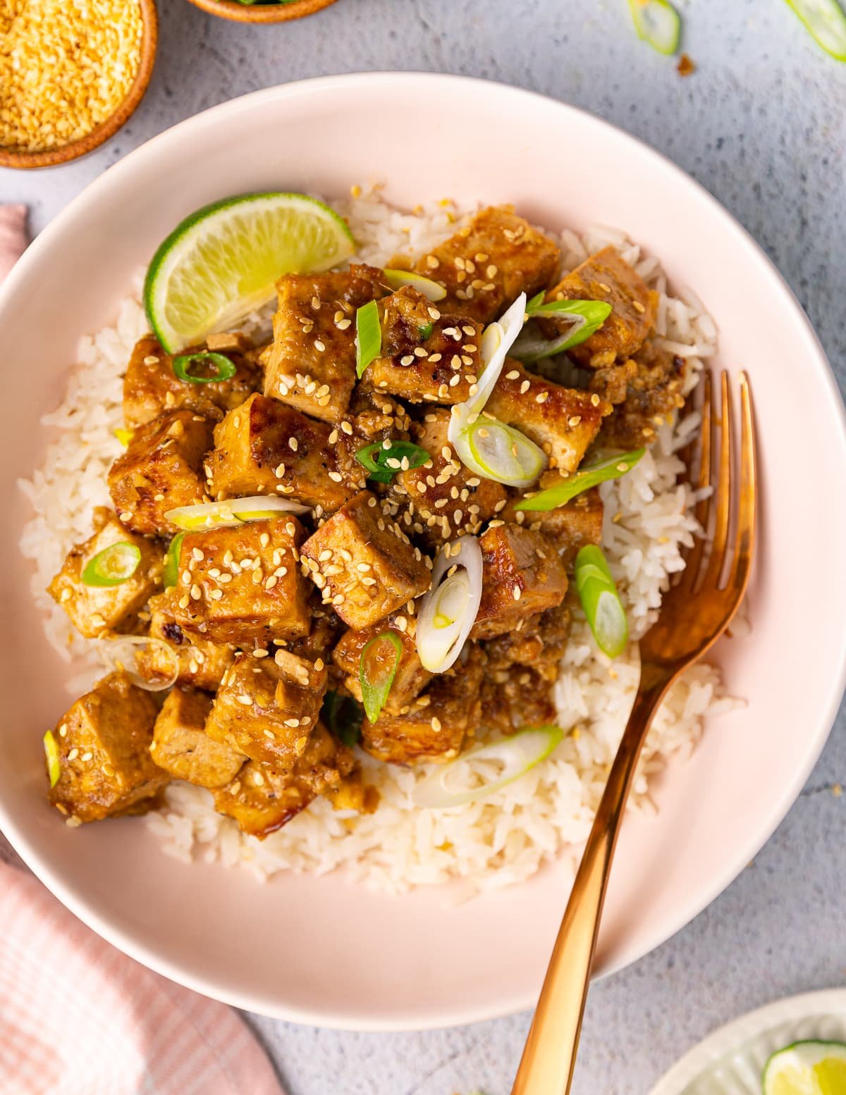 a bowl of ginger tofu and rice, with sesame seeds and a lime wedge