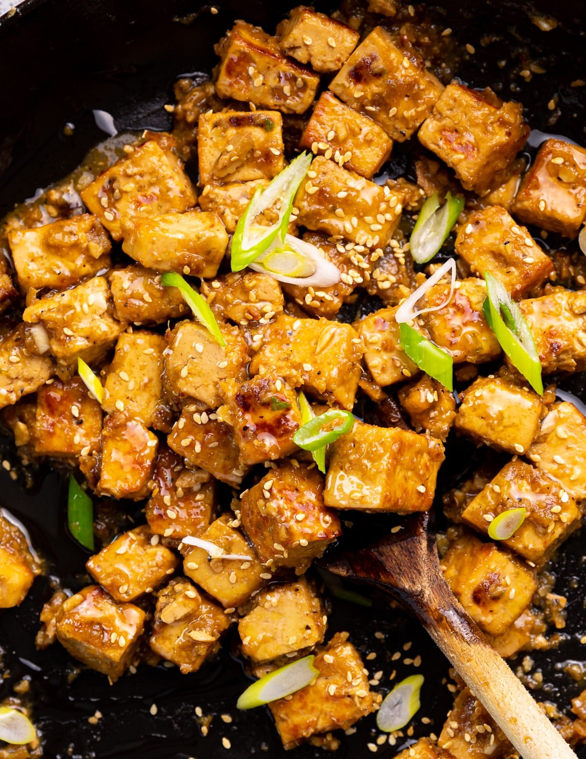 ginger tofu in a skillet with some sliced green onion as garnish