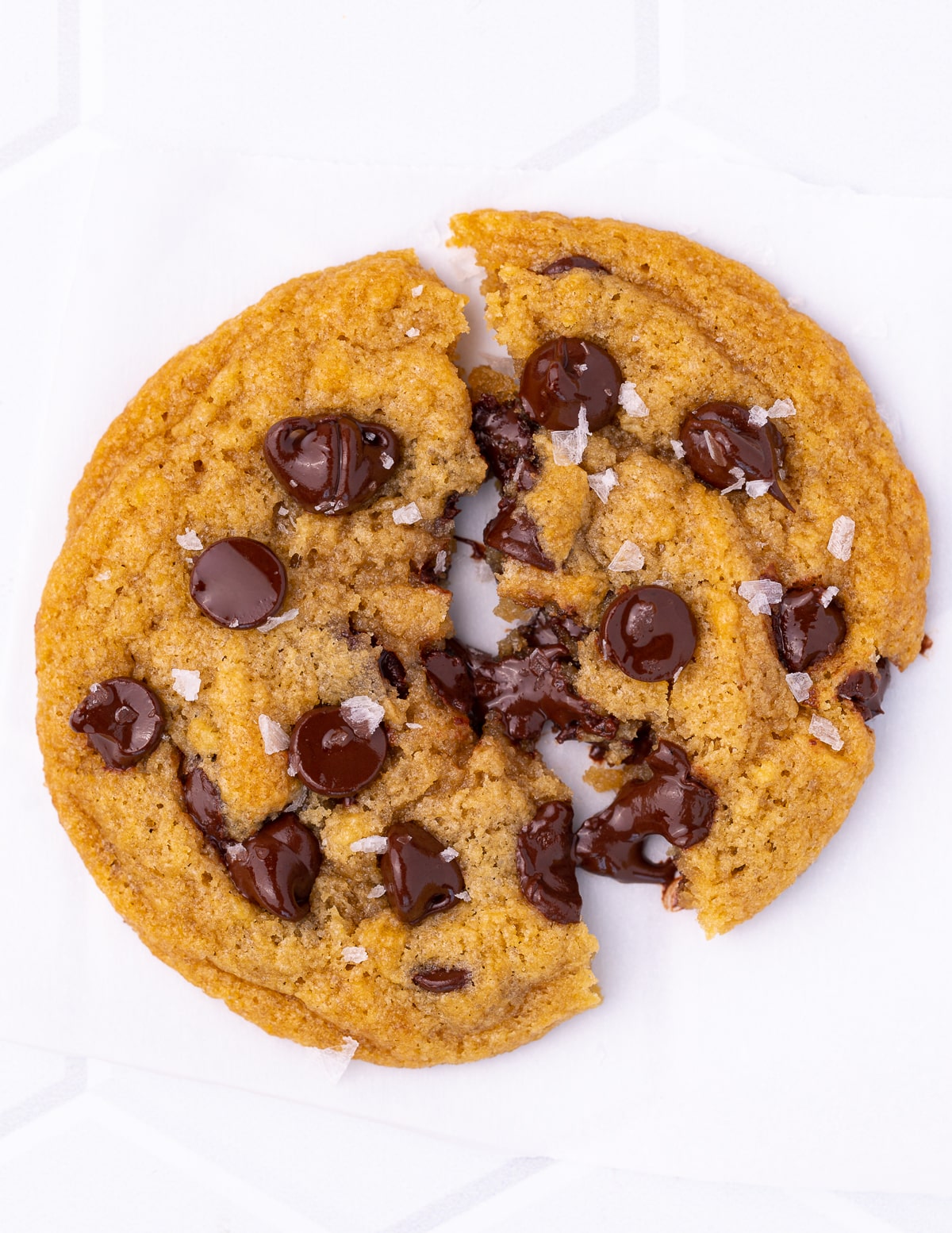 a chocolate chip cookie broken in half with gooey, melty chocolate