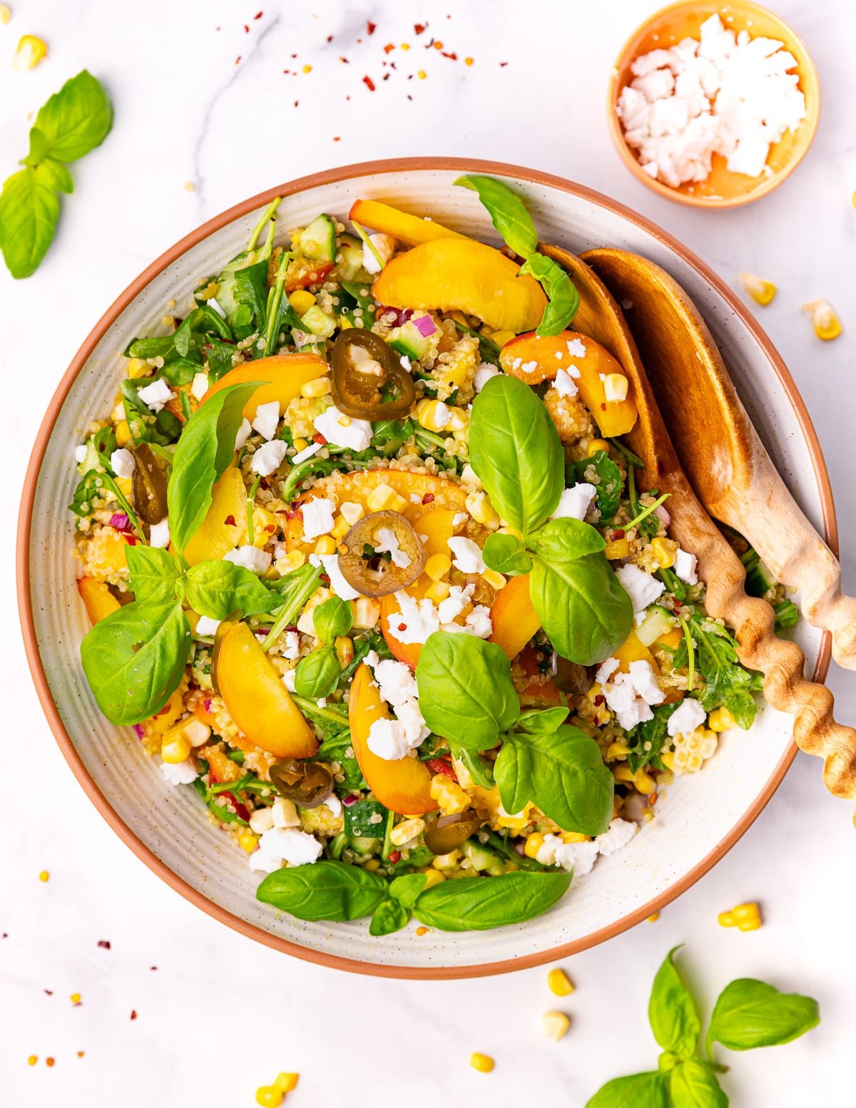 peach quinoa salad in a large salad bowl with wooden salad servers