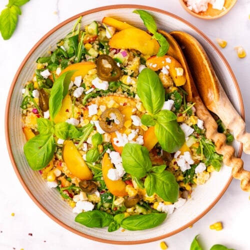 peach quinoa salad in a large salad bowl with wooden salad servers