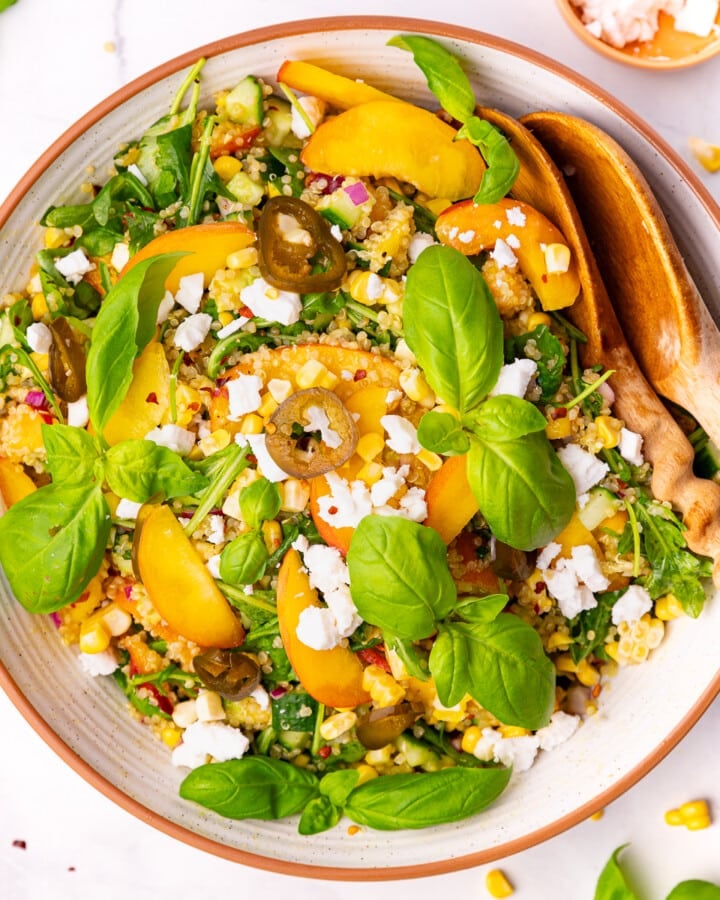 peach quinoa salad in a large salad bowl with wooden salad servers