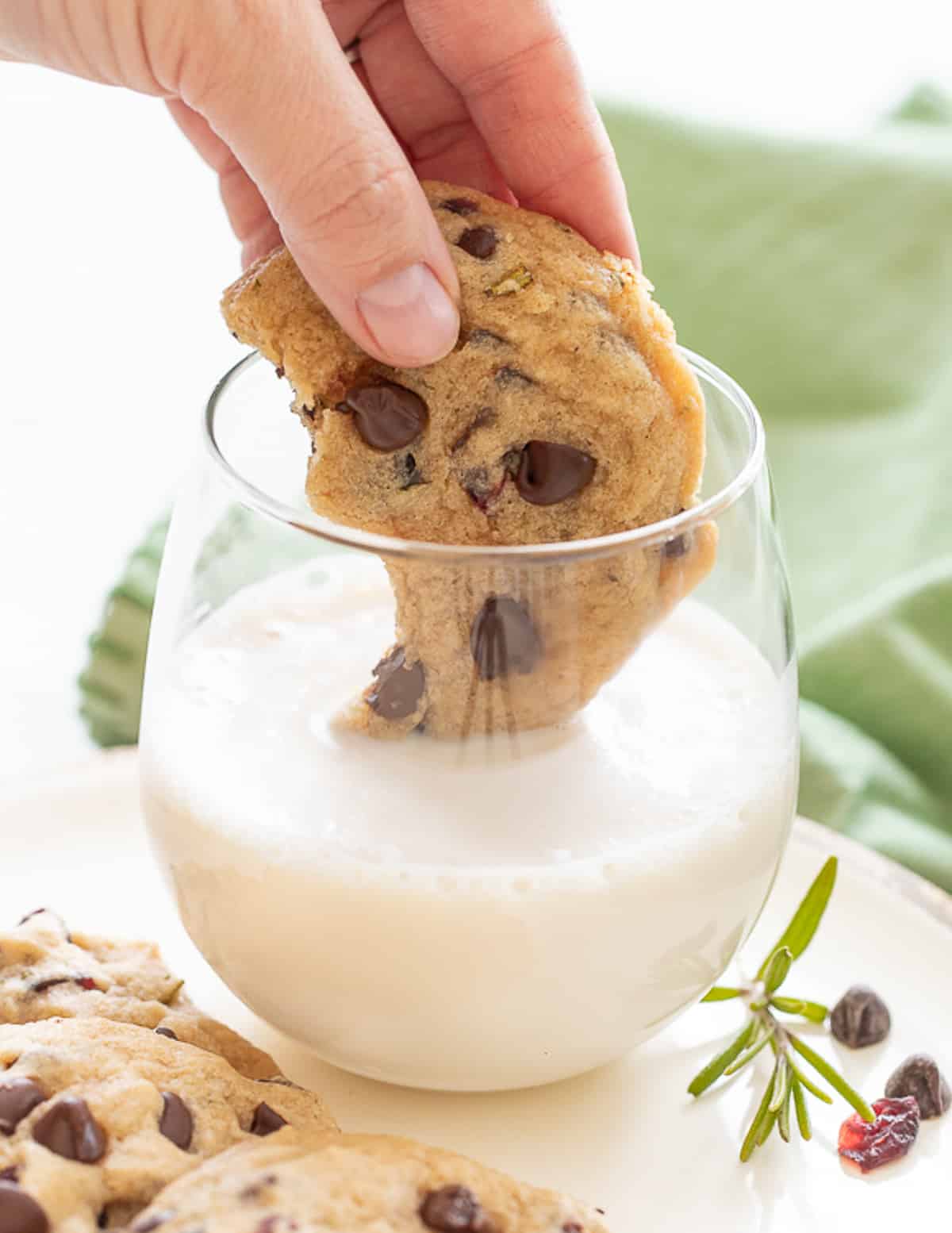 a cookie being dipped in a glass of almond milk