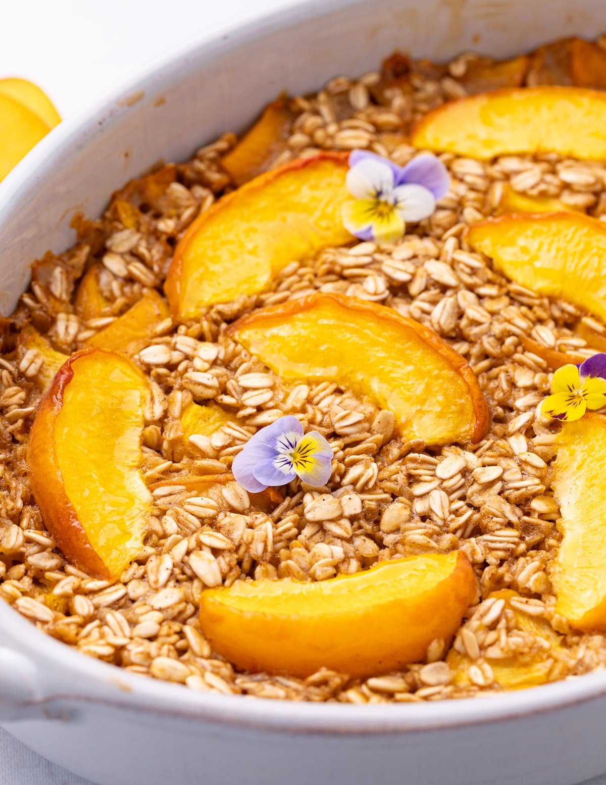 close up picture of baked oatmeal with some pretty little viola flowers for decoration