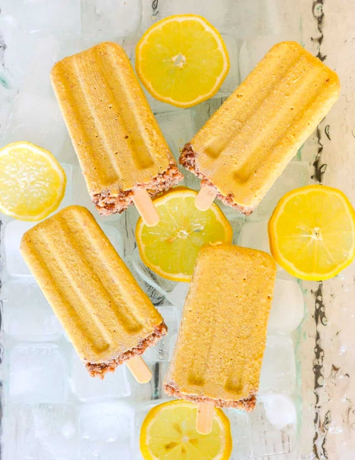 lemon cheesecake popsicles on a bed of ice and lemon slices
