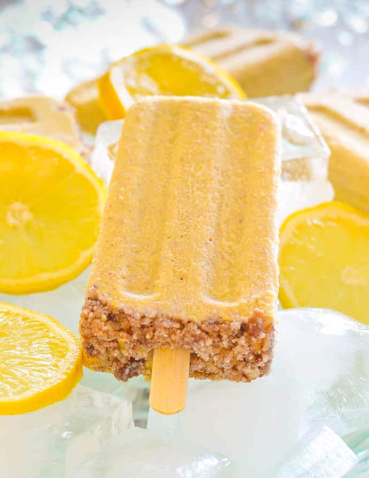 one healthy lemon cheesecake popsicle on a bed of ice