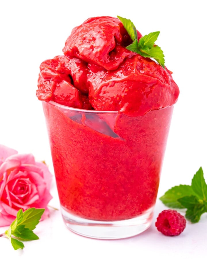 a glass of no churn raspberry sorbet garnished with a piece of mint