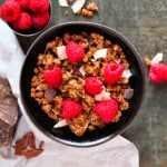a bowl of chocolate coconut granola with fresh raspberries