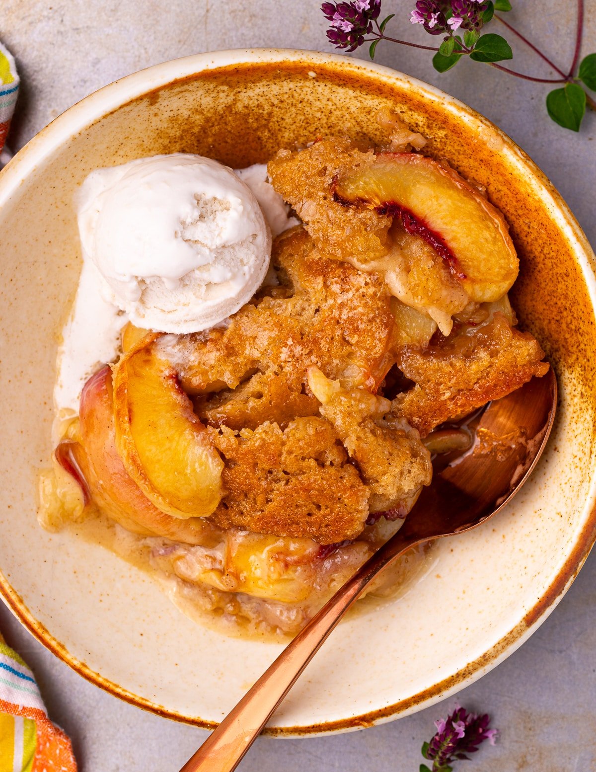 a bowl of vegan peach cobbler with a dollop of coconut ice cream