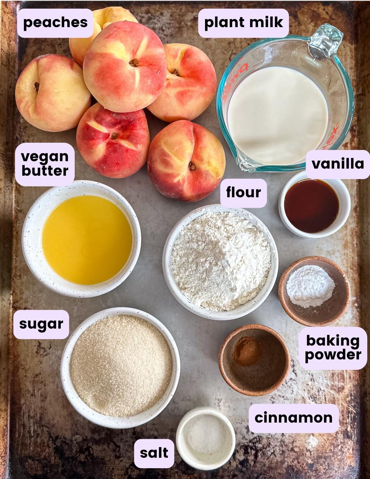 peaches, plant milk, vegan butter, flour, vanilla, baking powder, sugar, cinnamon and salt on a baking tray. 