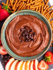 a bowl of dark chocolate hummus surrounded with fresh fruit and pretzels