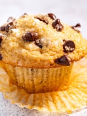 a chocolate chip muffin resting on a muffin liner