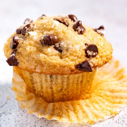 a chocolate chip muffin resting on a muffin liner