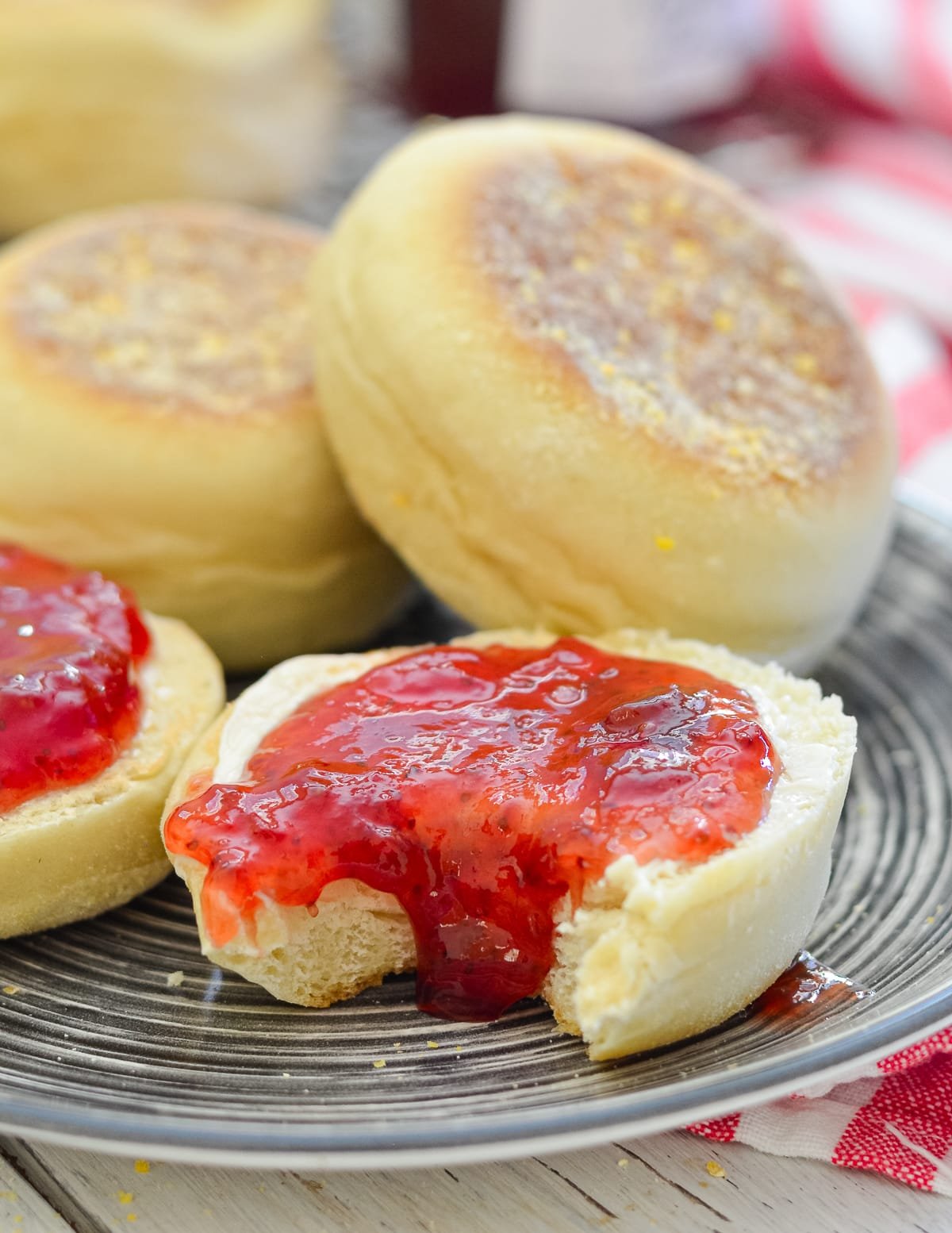 an English muffin half covered in jam with a bite taken out.