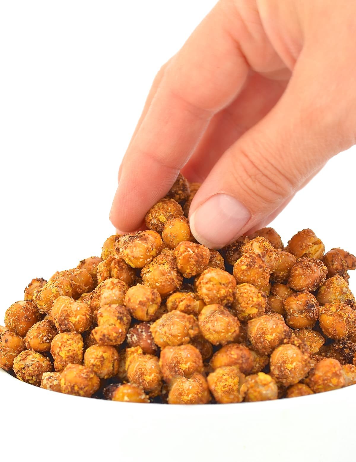 a hand taking some crispy chickpeas from a white bowl