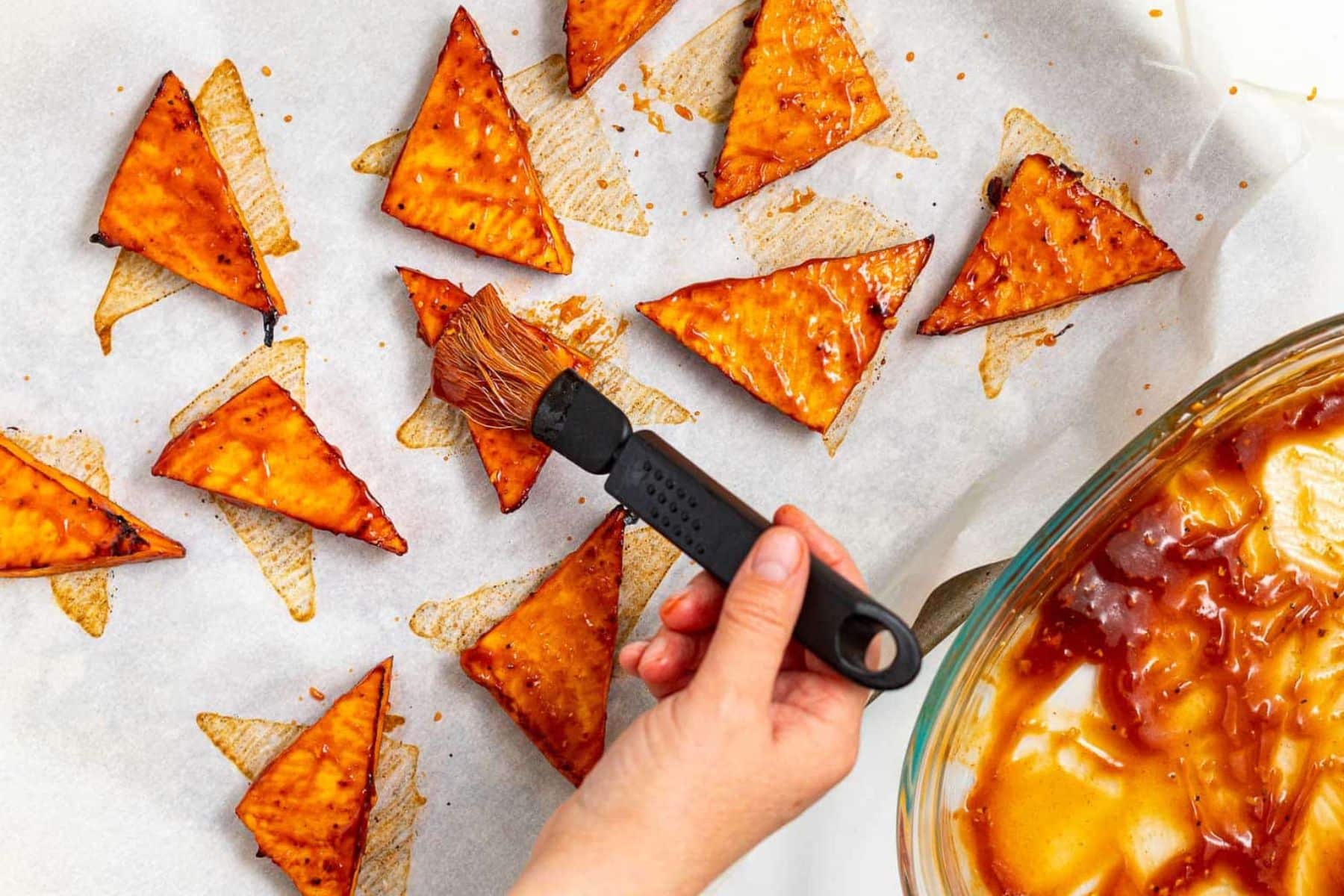 semi-cooked tofu triangles being brushed with more glaze