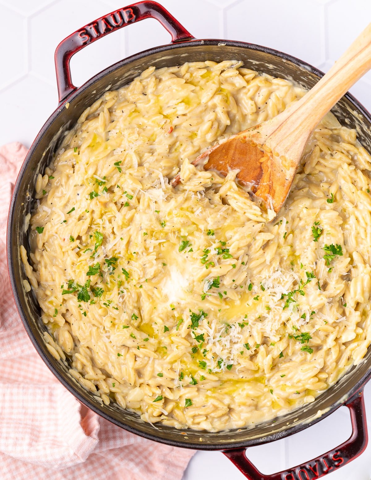 a pan of vegan orzo risotto garnished with vegan parm and parsley 