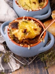 a bowl of vegan french onion soup in a blue soup bowl