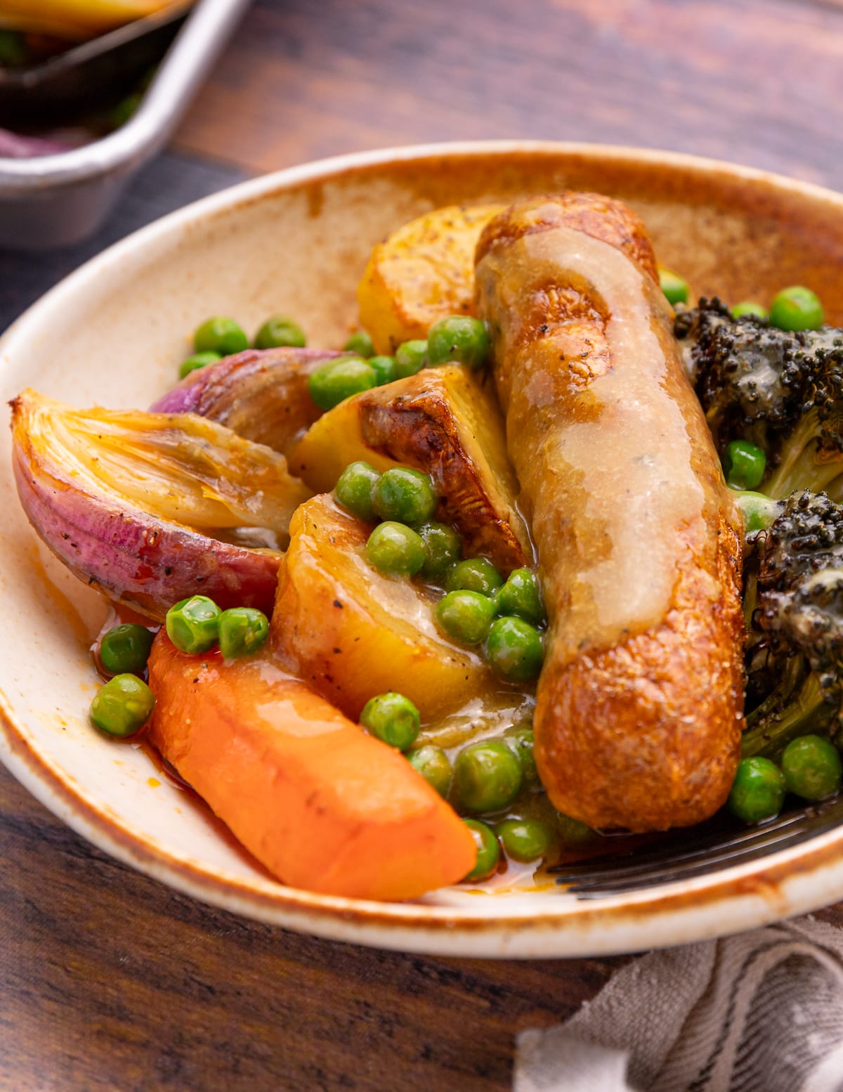 a bowl with a sausage, vegetables and gravy