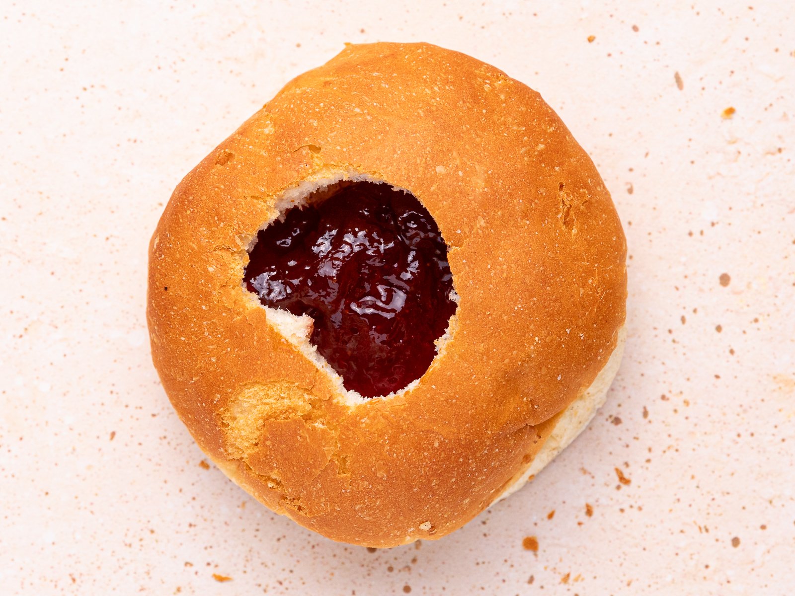 a bread roll with a hole filled with jam 