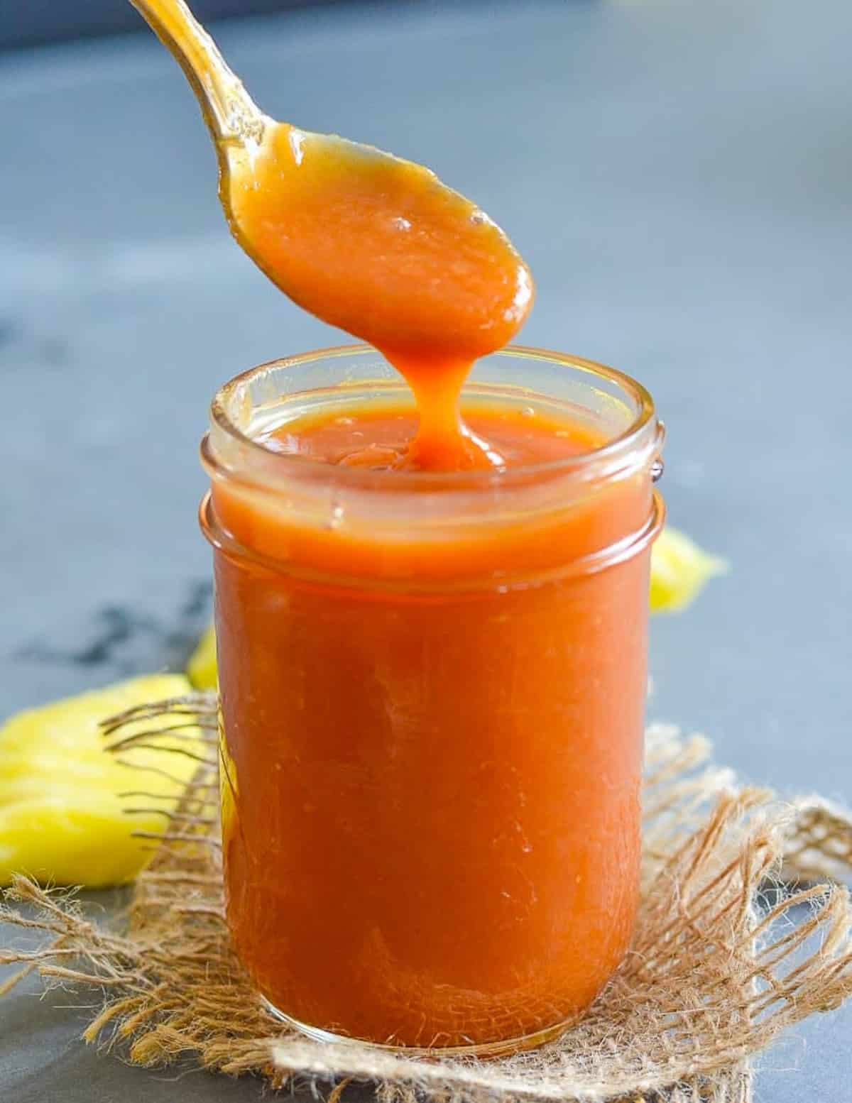 a spoonful of heathy sweet and sour sauce held over the jar 
