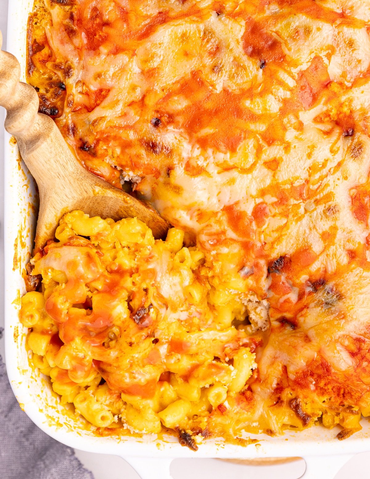 close up of a wooden spoon scooping vegan buffalo mac and cheese out of a casserole