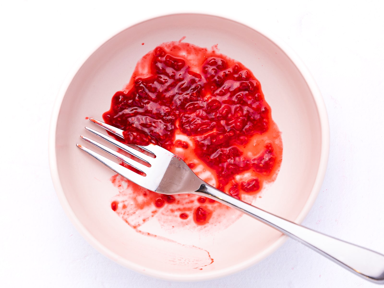 fork smushed raspberries in a small bowl