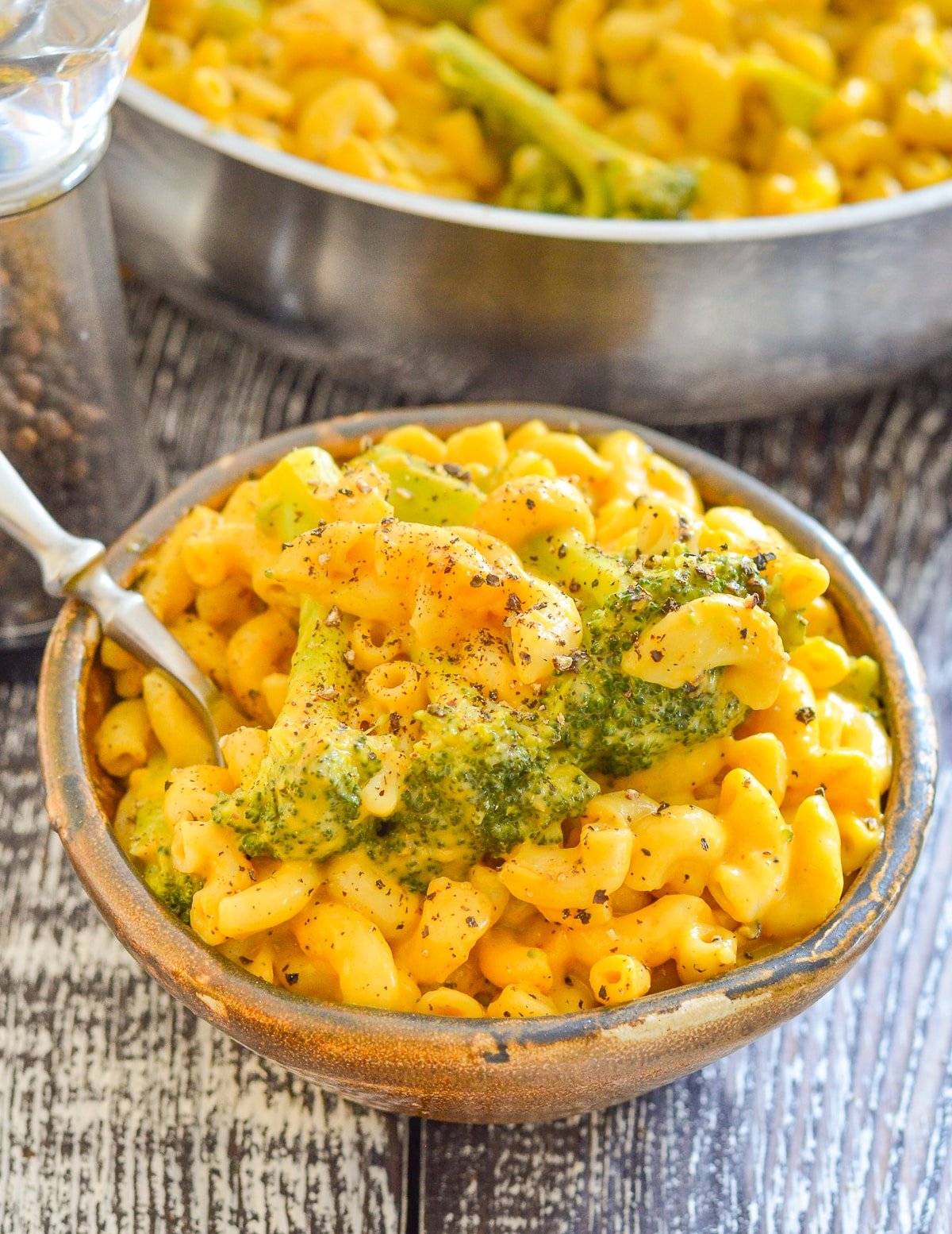 a bowl of mac and cheese with broccoli and black pepper