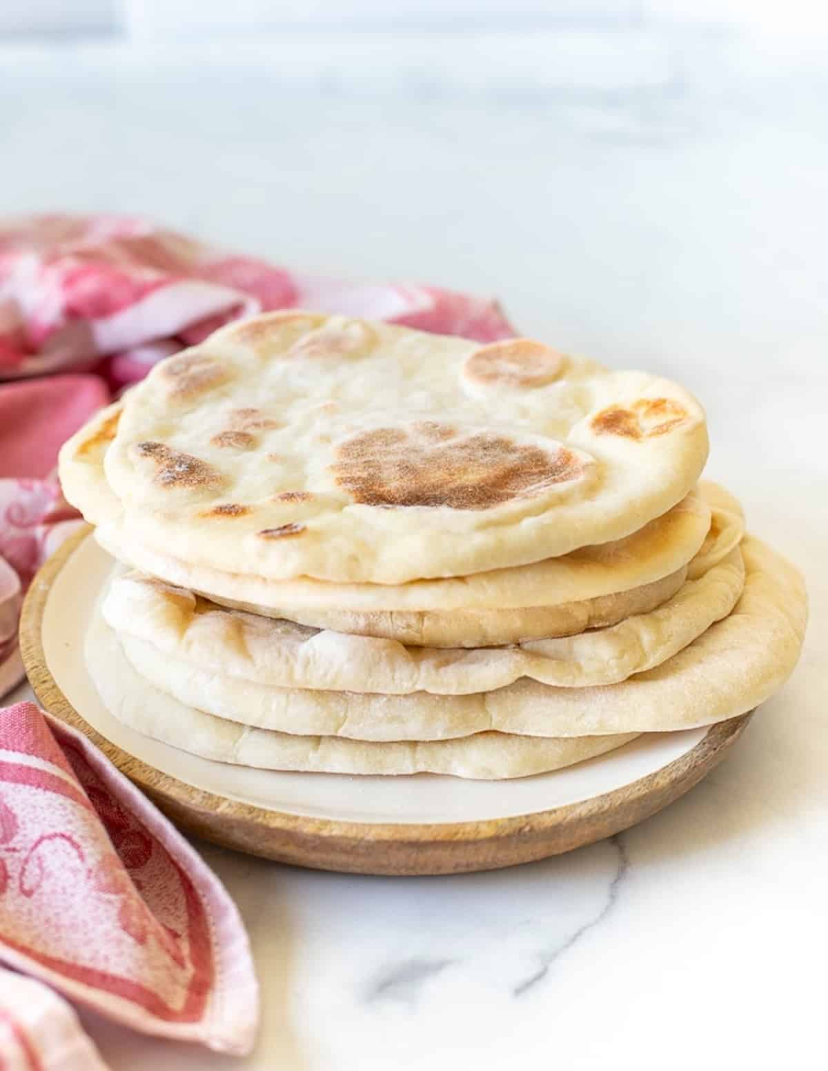 a stack of flatbreads on a plate  with a pink cloth in the background