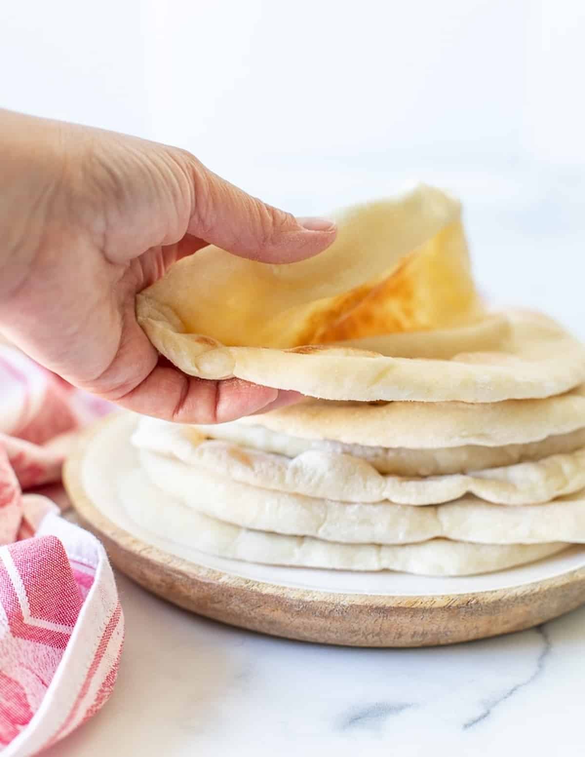 a hand taking a flatbread from the top of a stack 