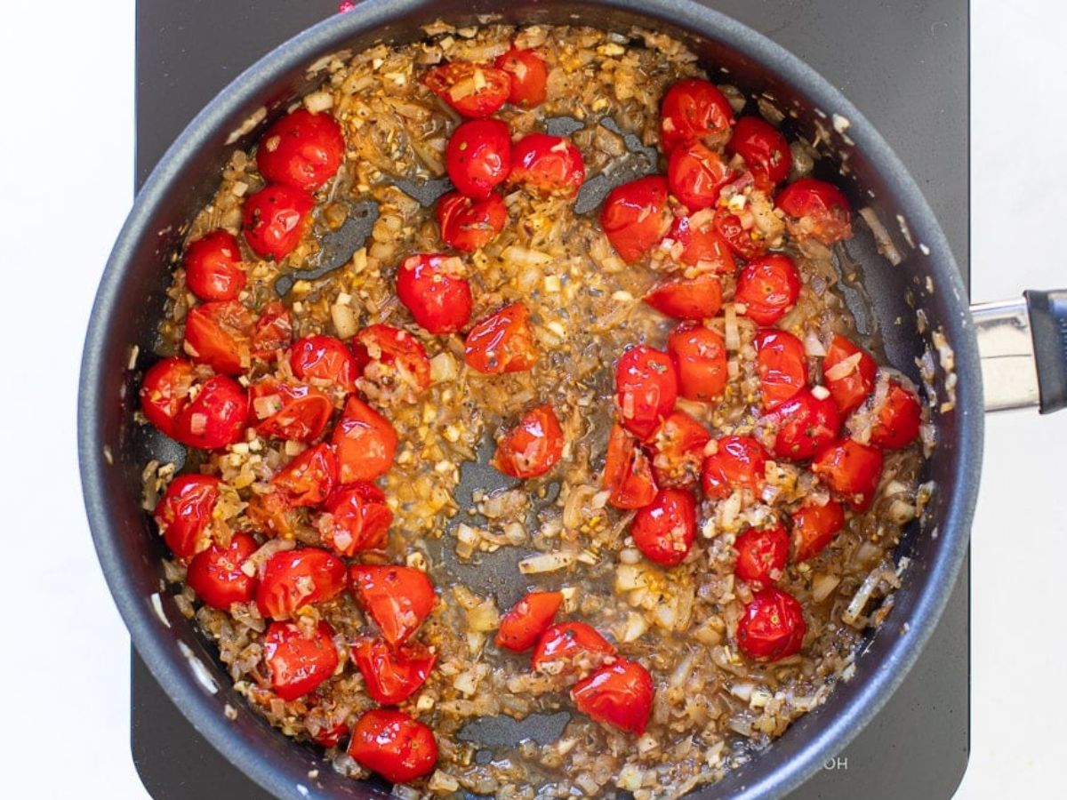onions and cherry tomatoes cooking in a pan