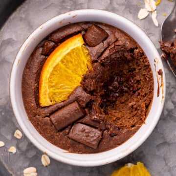 a ramekin of chocolate orange blended baked oats with a big spoonful taken out to show the fudge melty chocolate inside.