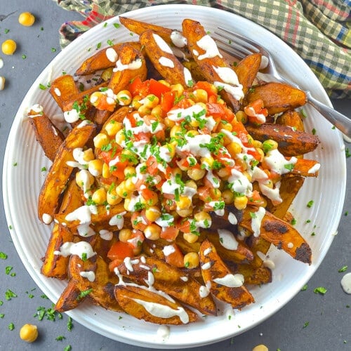 a plate of loaded taco fries drizzled with lime crema.