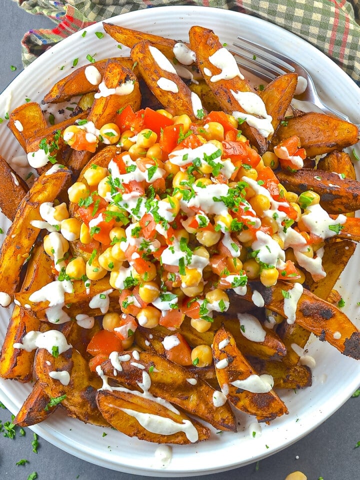 a plate of loaded taco fries drizzled with lime crema.