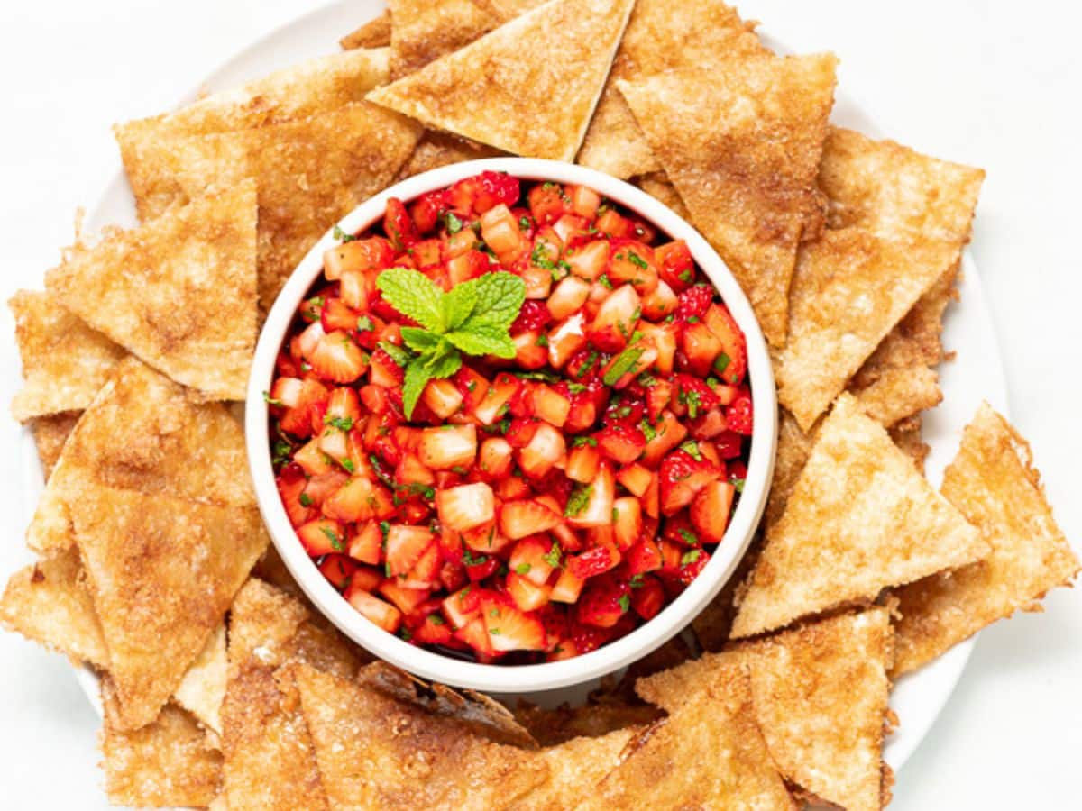 a bowl of strawberry salsa surrounded by crispy cinnamon tortilla chips