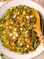 a bowl of crispy quinoa kale salad with wooden salad servers