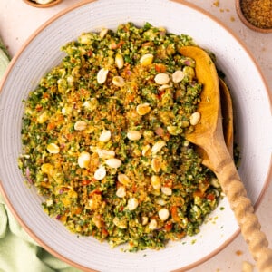 a bowl of crispy quinoa kale salad with wooden salad servers