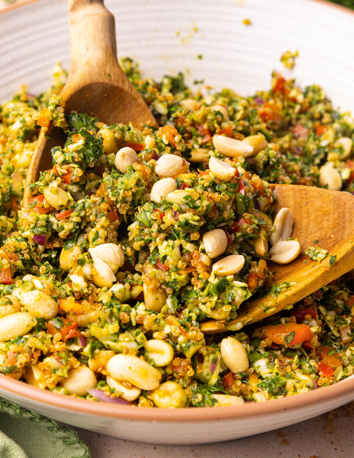 a close up of wooden salad servers picking up some kale quinoa salad