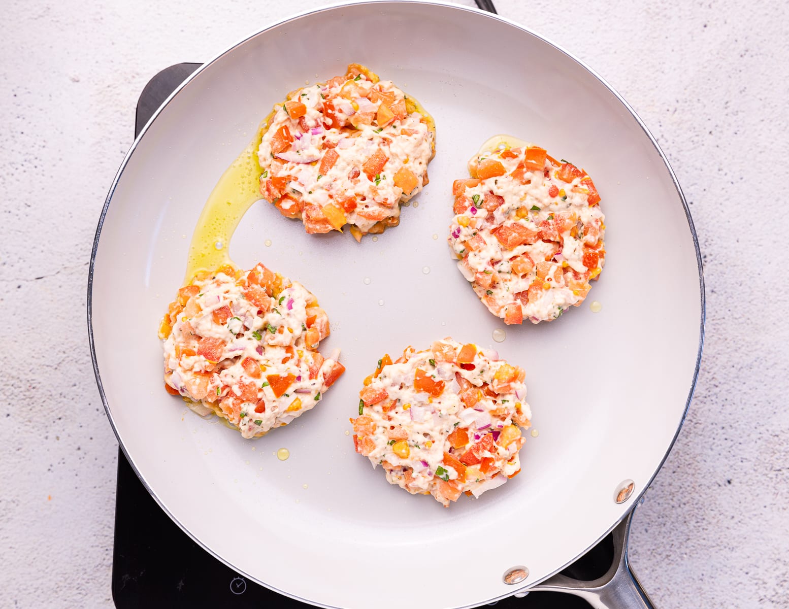 uncooked tomato fritters in a frying pan