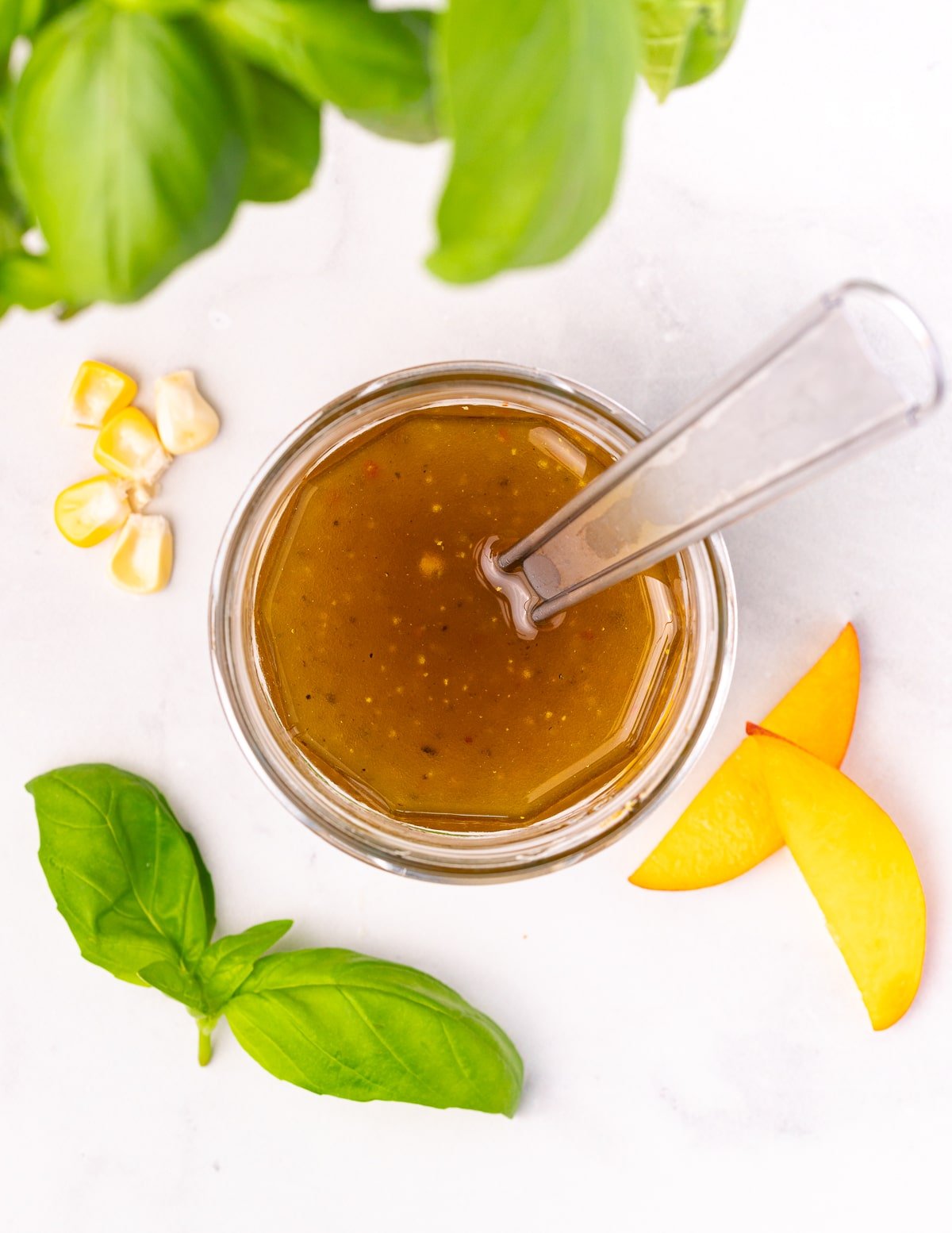 a jar of vinaigrette with a small whisk in it. 