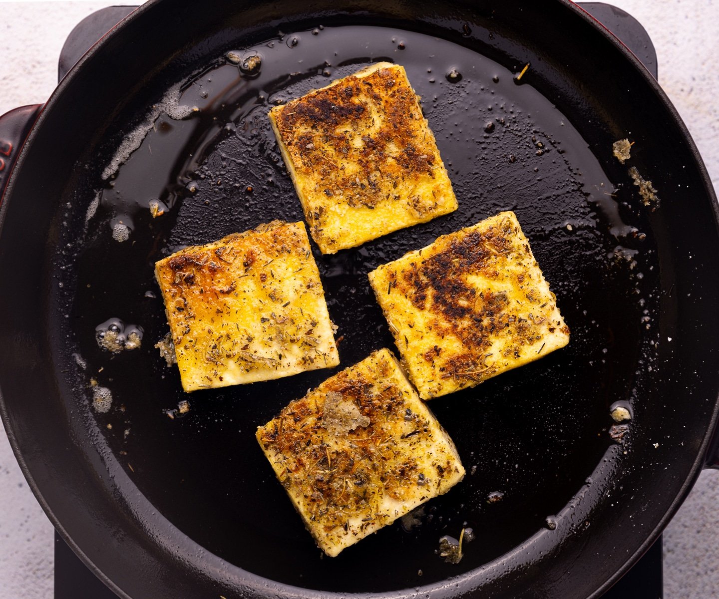 golden, crusty, and herby tofu squares in a skillet. 