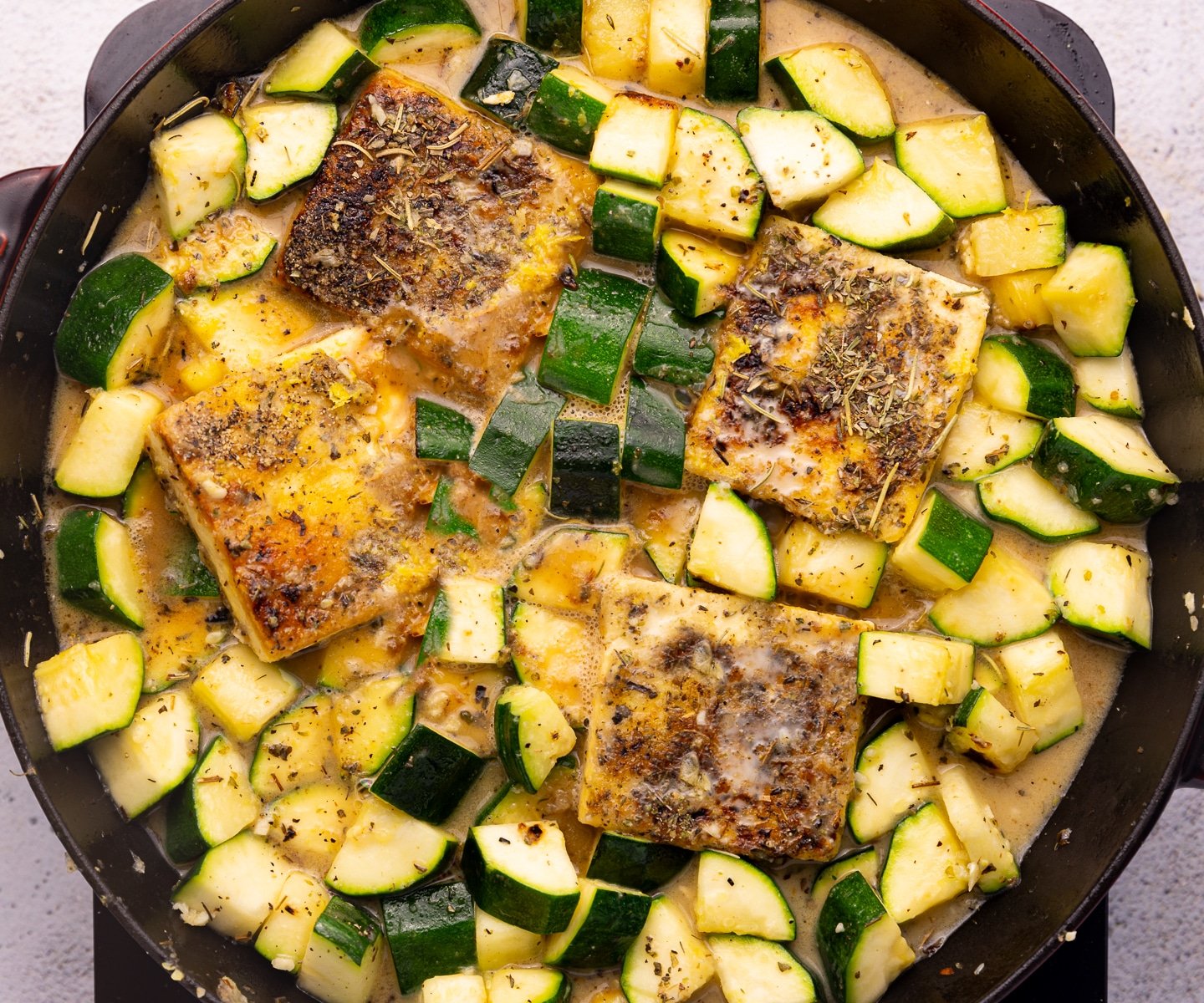 golden tofu and zucchini in a skillet with lots of sauce. 