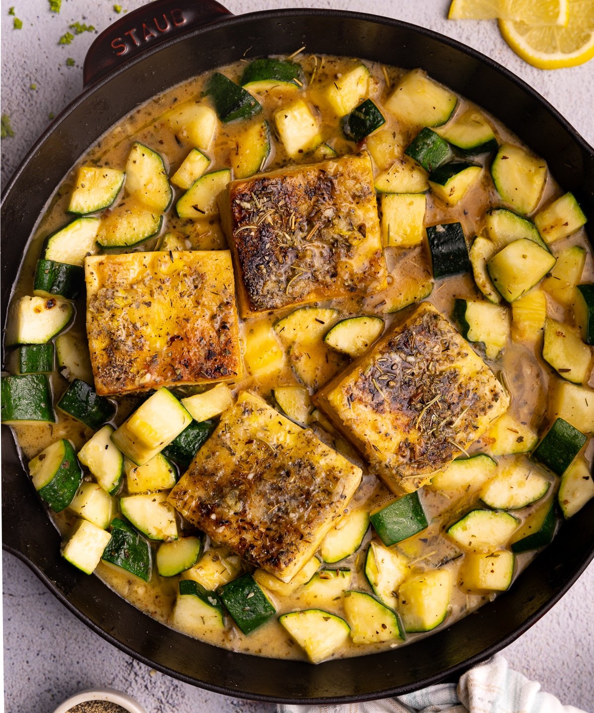 a Staub skillet with golden, herby tofu and zucchini pieces in a herby sauce. 